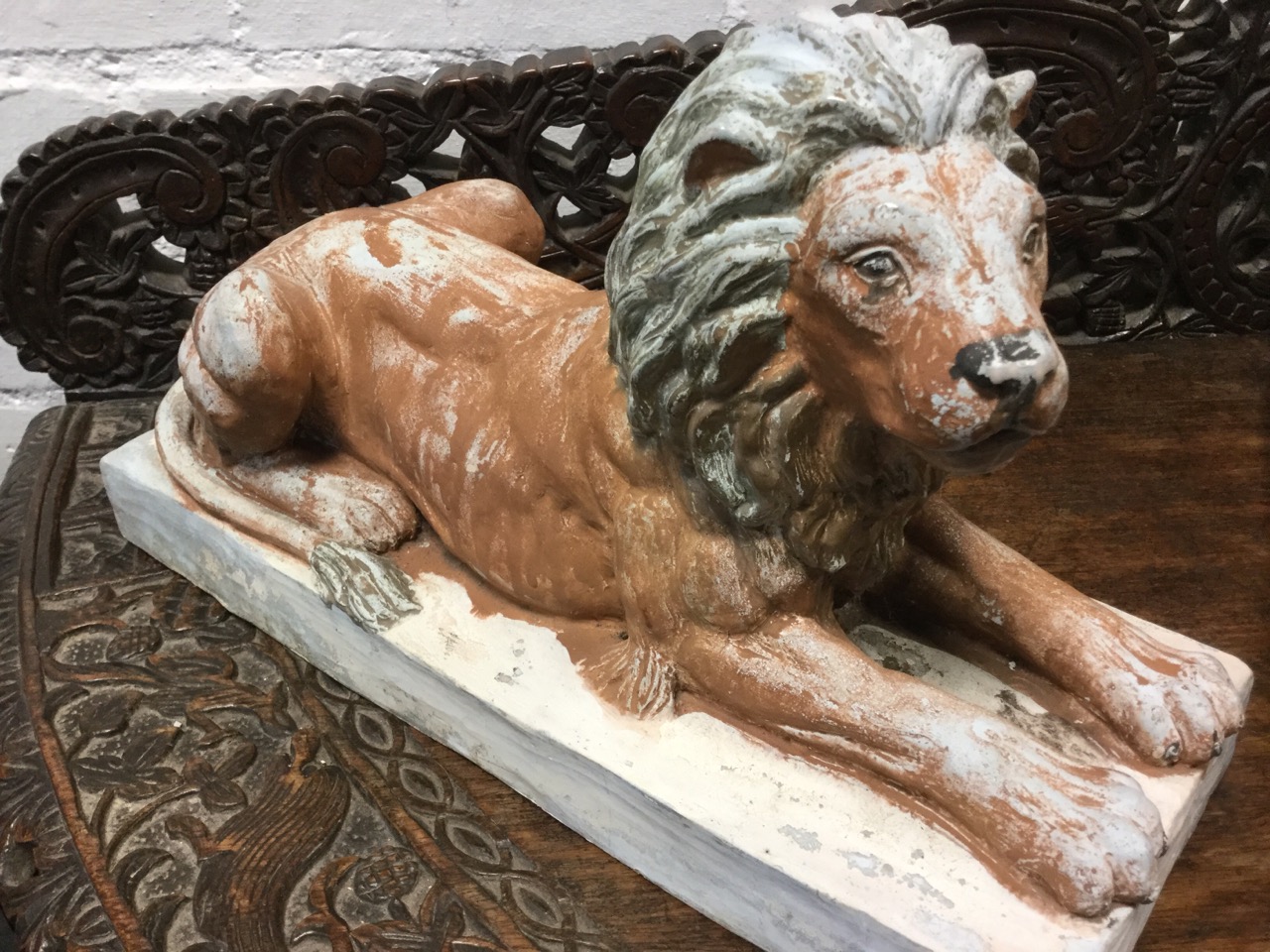 A pair of composition lions, the painted animals lying in prone positions on rectangular plinths. ( - Image 2 of 3