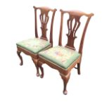 A pair of George II walnut side chairs, the undulating rails above pierced vase splats, the