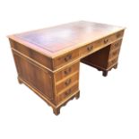 A yew partners desk with gilt tooled leather skiver to rectangular moulded top above three frieze