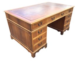 A yew partners desk with gilt tooled leather skiver to rectangular moulded top above three frieze