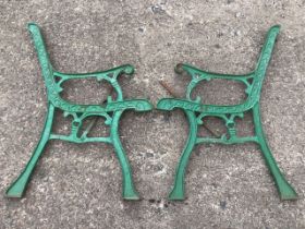 A pair of cast iron bench ends with scrolled decoration to chanelled frames, raised on sabre