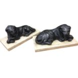 A pair of Victorian lead lions, the beasts lying on rectangular marble plinths with crossed paws. (