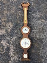 A beech framed barometer, the broken pediment with urn finial above a shaped case with