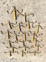 Nineteen Victorian coathangers, the brass hooks above swivelling shaped hooks, on turned wood