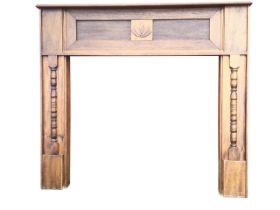A 1920s oak fire surround, the moulded mantel above a deep frieze with two panels centering a leaf