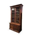 A Victorian mahogany bookcase, the moulded cornice above a pair of arched glazed doors flanked by