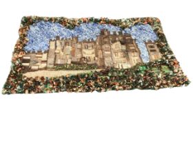A mixed hookie, proggie and applique textile wall hanging depicting a castle, framed by tufted