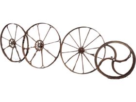A pair of large iron agricultural wheels, each with eight shaped riveted spokes, the central hubs