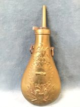 A US civil war style peace powder flask embossed with eagle and clasped hands above shield weapon