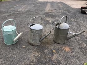Two three-gallon galvanised watering cans with angled straight spouts and fixed loop handles; and