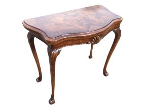 A Georgian style walnut fold-over card table, the serpentine moulded top opening to a baize interior