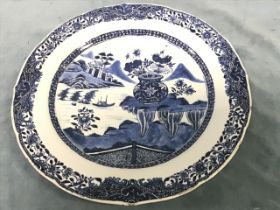 A Chinese blue & white export plate decorated with water landscape and vase of flowers within a
