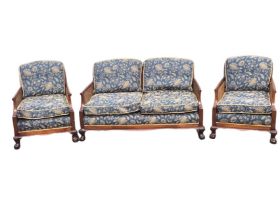 An Edwardian mahogany three-piece bergere suite, with undulating crest rails above caned backs and