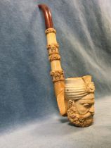 A Turkish meerschaum pipe by Nurhan, the bowl carved as a bearded head, the stem with bands of