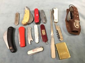 A collection of pocket knives including Swiss Army style, camping advertising, bottle openers, a