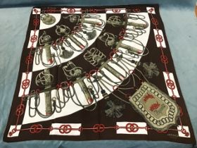 A Hermes Paris brown silk scarf printed with a curved display of sword hilts, titled Cliquetis. (