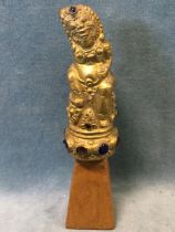 An antique Balinese gilt metal kris handle in the form of a Hindu deity, inset with blue and amber