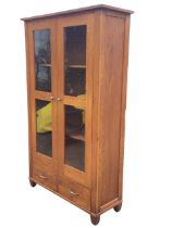 A Marks and Spencer oak cabinet, the overhanging top above a pair of glazed doors with metal knobs