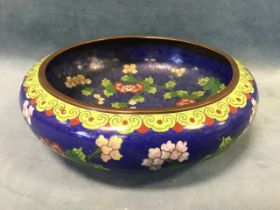 A Chinese cloisonné bowl decorated with blossom foliage on a deep blue ground, the underside with