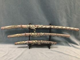A trio of Japanese swords by Ancient Warrior with faux snakeskin scabbards and moulded dragon