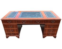 A reproduction yew kneehole desk, the rectangular moulded top with gilt tooled leather skivers above