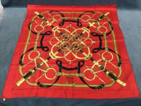 H d’Origny, a Hermès Sellier red silk scarf depicting spurs, black and gold straps, chains, etc.,