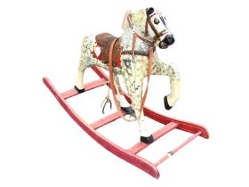 A C20th carved rocking horse, the later dapple painted beast in prancing pose with leather saddle