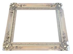 A Victorian gilt gesso picture frame, with rococo scrolled corners flanked by trailing foliage