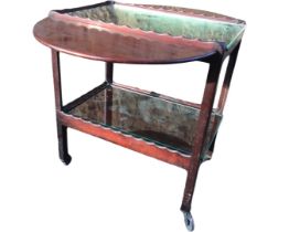 A mahogany supper table with rounded drop-leaves, the tray top trolley with two scalloped shelves