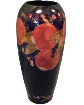 A tall tapering Moorcroft tube lined vase decorated with pomegranates on blue ground - signed and