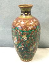 A Japanese cloisonné vase decorated with butterflies and scrolled blossom foliage on green chip