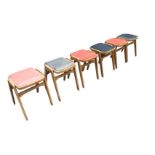 A set of six mid-century beech stacking stools, the rounded square upholstered seats on raked