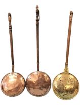 Three Victorian copper and brass bed warmers, the circular pans with punched and pierced decoration,