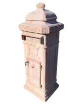 An iron postbox cast as a rectangular column with scrolled classical panels, the cover with crown