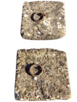 A pair of square composition stone tether stones or flag covers, the panels cast with iron rings. (