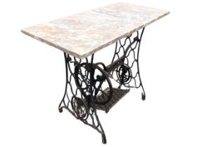 A cast iron Singer sewing machine table with pierced supports framing treadle mechanism, fitted with