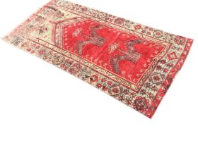 A Baluch wool prayer rug, the red ground with plant motifs within leaf & ribbon and flowering branch