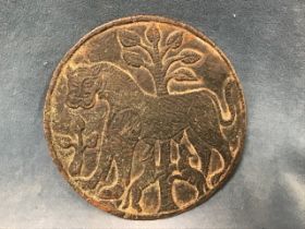 A cast bronze circular plaque depicting a lioness feeding two cubs, with trees in the background. (