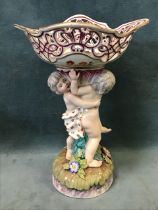 A C19th Continental porcelain entree dish, the pierced scalloped bowl raised by twin cherubs on