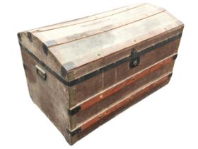 A domed top seamans chest with studded slats and iron mounts on canvas ground, with carriage handles