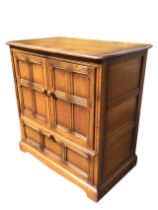 An Ercol elm Old Colonial pattern cabinet, the rounded rectangular top above a pair of four panel