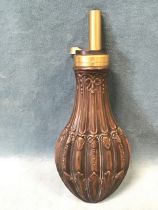 A copper powder flask with fluted leaf embossed body and scrolled collar, having brass spout. (8.