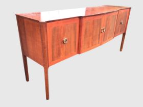 A mid-century mahogany sideboard, the shaped top with canted corners above four crossbanded doors