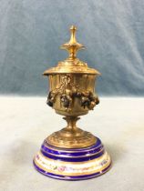 A C19th French porcelain mounted ormolu inkwell, the hinged cover with turned finial above a