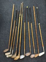 A collection of hickory shafted golf clubs, drivers, mashies, mashie niblicks and putters by various