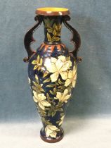 A Doulton Lambeth Faince vase of slender shape, decorated with flowers on blue ground, the neck with