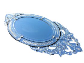 A Venetian style oval wall mirror, the pierced foliate crest, apron and frame with engraved and