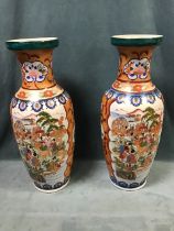 A pair of Chinese style vases decorated with figural panels and floral cartouches on orange