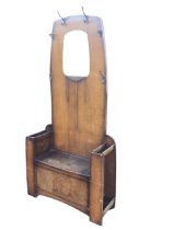 A deco oak hallstand, the back with carved floral plaque beneath an arched mirror, fitted with