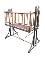 A Edwardian mahogany cot, with turned finials and spindle sides, swinging on a trestle stand with